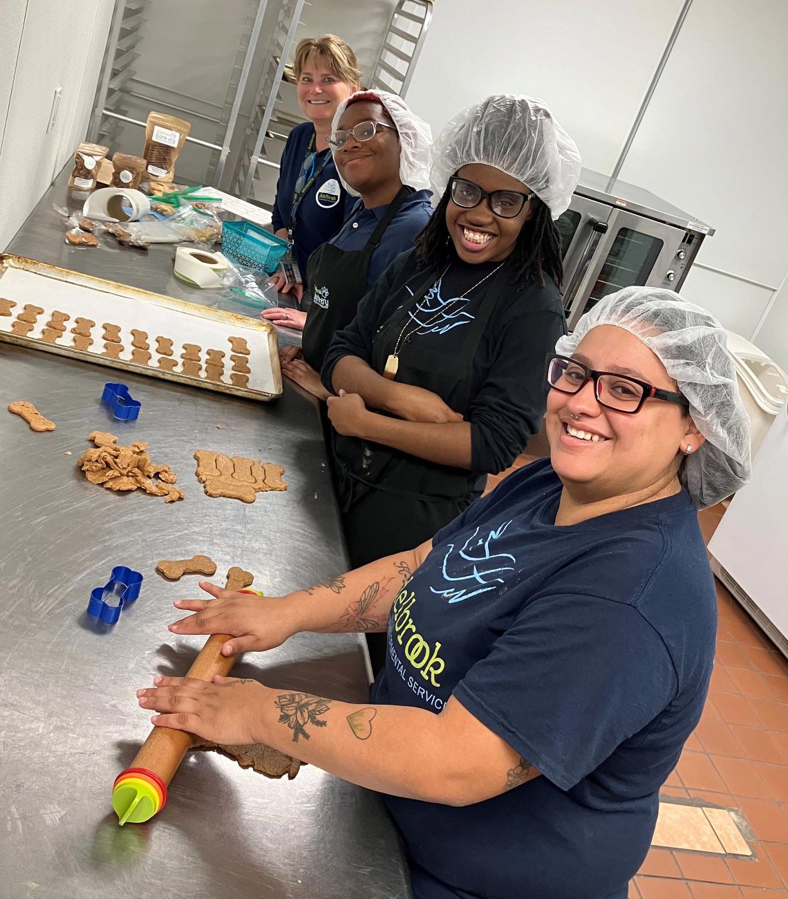 Four people smiling while making dog treats