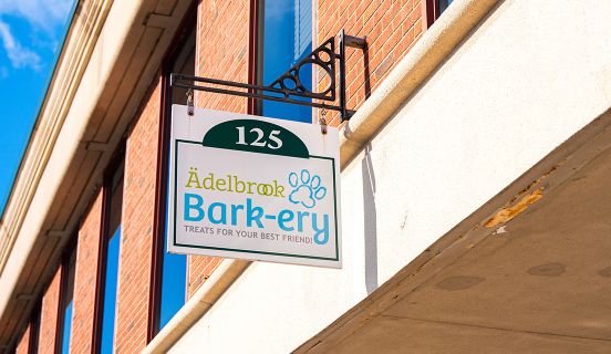 An outdoor storefront sign that says "Adelbrook Barkery: Treats for Your Best Friend"