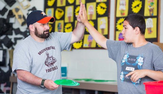 An older man high-fiving a young boy