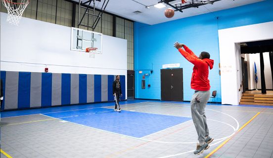 A boy shooting a basketball in an indoor basketball court