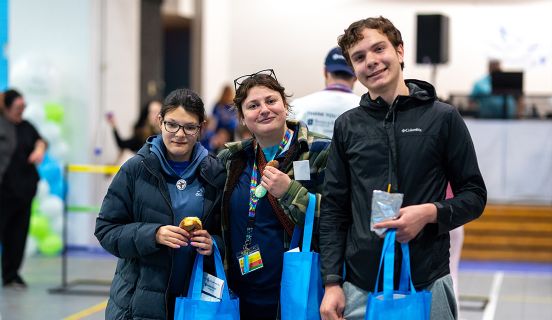 Three people smiling and holding blue bags