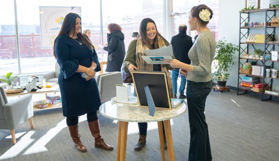 Three people gathered around a table talking to one another