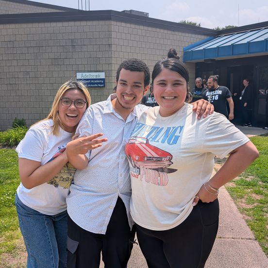 Three people standing together in a hug, smiling. 