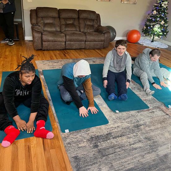 Four young adults sitting on yoga mats on the ground