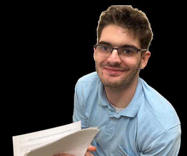 Young man in a light blue polo, smiling for a photo, holding papers