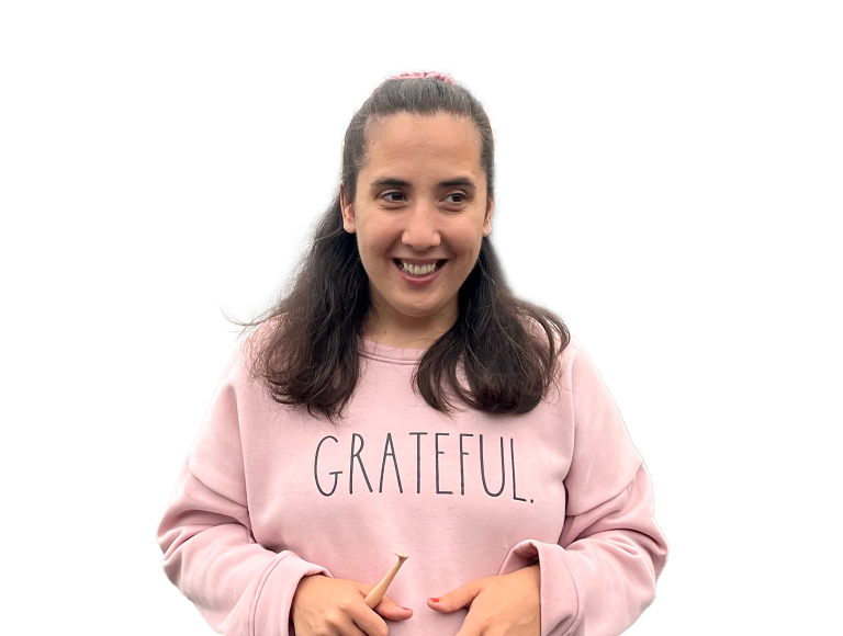 A brunette girl wearing a blush pink crewneck that says "grateful."