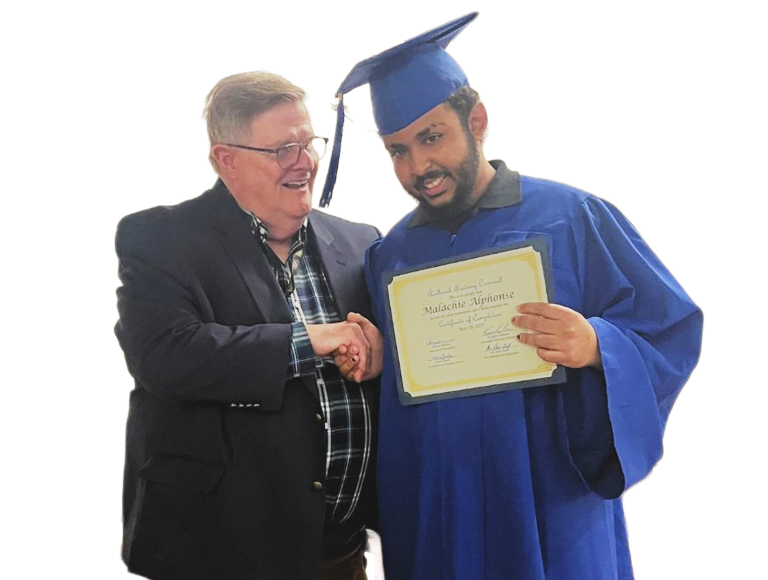 Older man shaking hands with a student wearing blue regalia and holding a diploma