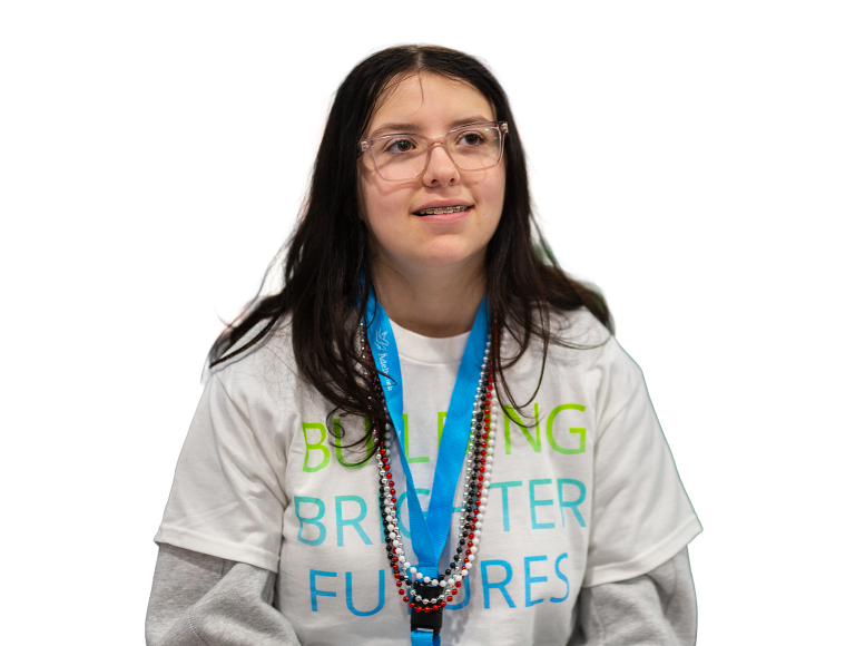Young girl smiling while wearing a white Ädelbrook shirt that says "Building Brighter Futures"