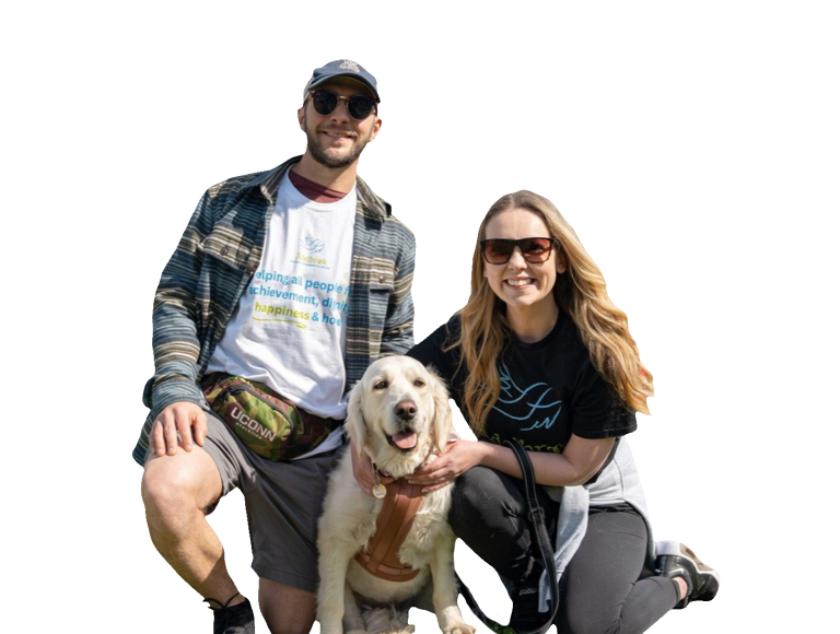 A man and a woman smiling with a dog while wearing Ädelbrook t-shirts