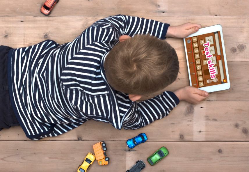 A little boy in a black and white stripped hoodie, using an app on a tablet. 