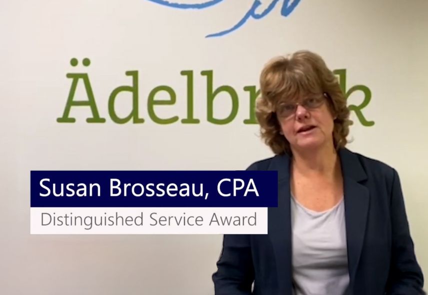Susan Brosseau wearing a blazer standing by a wall reading "Adelbrook"