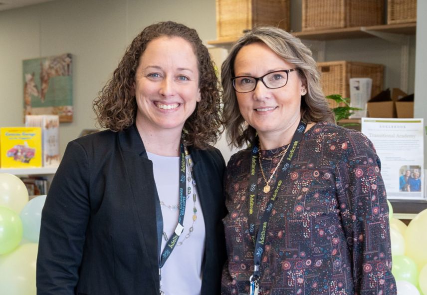 Two women smiling next to each other in front of books