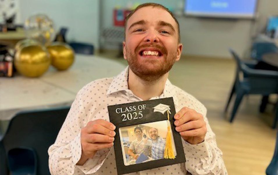 Young man in a butto-down shirt, holding a picture of him with text that says, "Class of 2025"