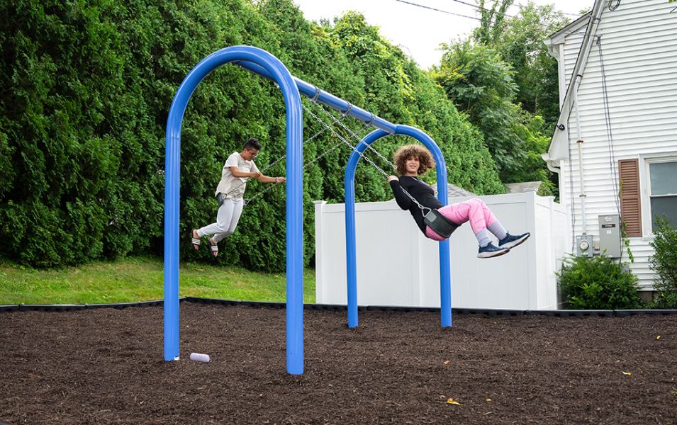 Two kids playing on a swingset